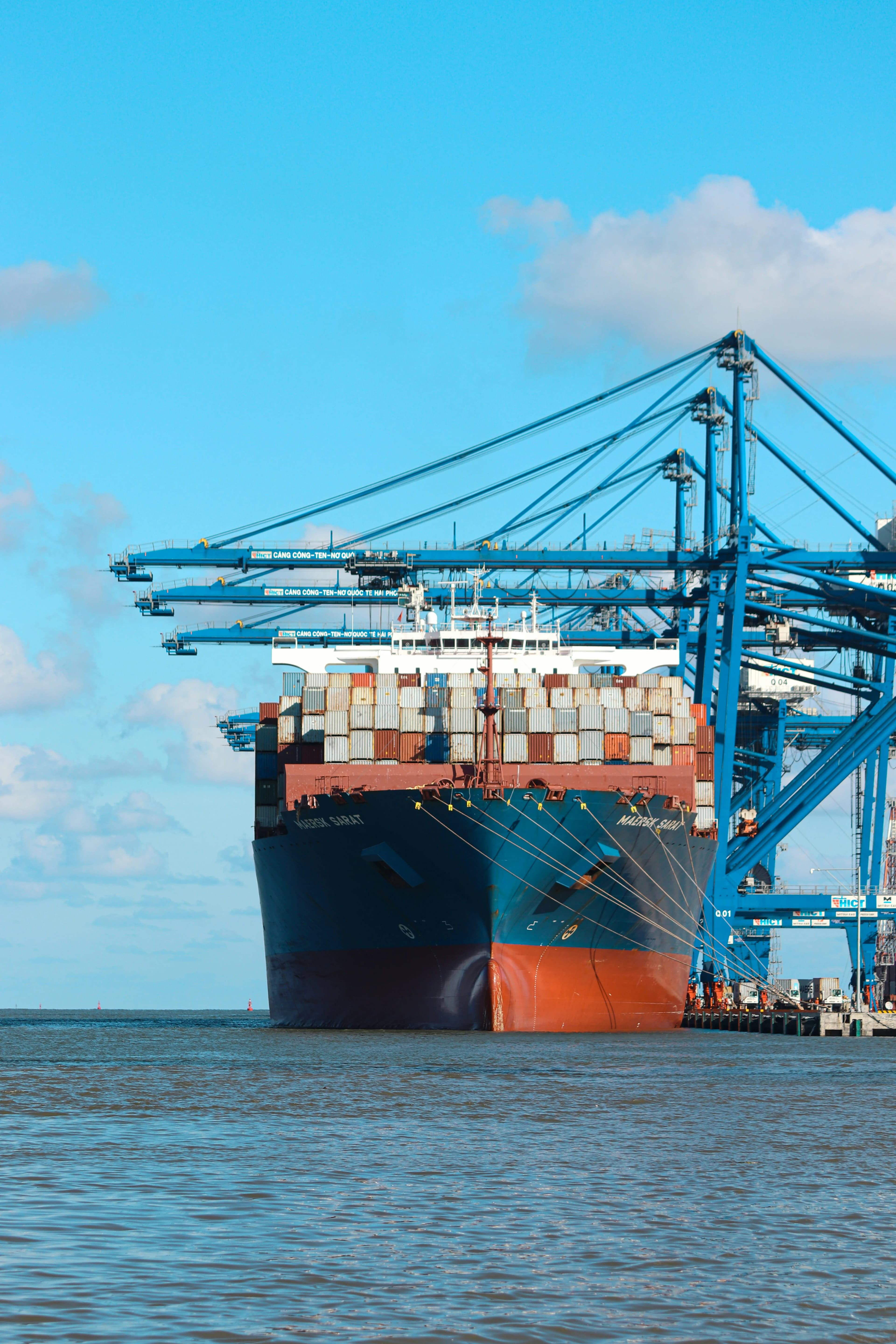 Container ship berthed at a port beneath gantry cranes
